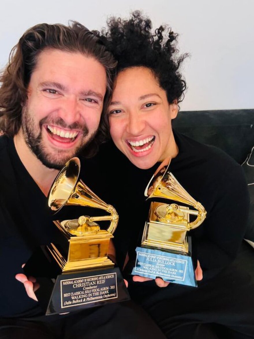 A man and woman holding Grammy awards smile widely.