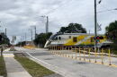 A Brightline train passes behind a crossing gate on WH Jackson Street in Melbourne, where company workers have added traffic delineation posts to deter drivers from trying to drive around the gate when it's down.