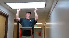 Cleon Ludwick installs the new energy-efficient lights in Western Michigan University's Friedmann Hall. If you look closely, you can see how blue the new lights look compared to the more yellow lights down the hall