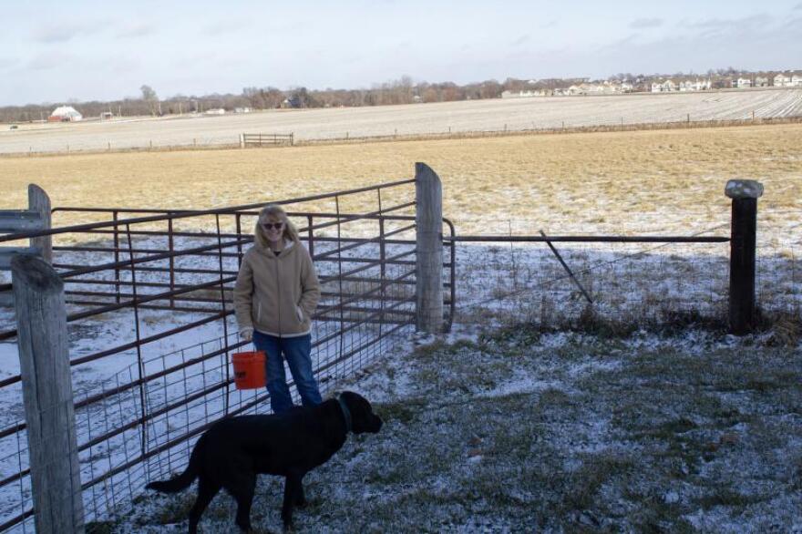 woman and her dog standing in a gated area 