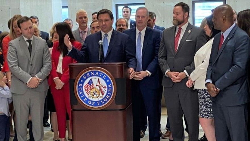Gov. Ron DeSantis (at podium)