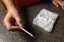 Chris holds a plastic syringe he and his wife use to administer homemade medical marijuana oil to their 13-year-old son, Dylan, who has autism.