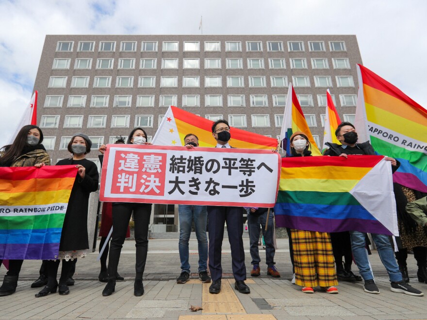 Supporters celebrate the district court's ruling on Japan's same-sex marriage ban with a flag reading "unconstitutional decision" in Sapporo, Hokkaido prefecture, on Wednesday.