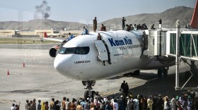 Afghan people climb atop a plane as they wait at the Kabul airport in Kabul on Aug. 16, 2021. (Wakil Kohsar/AFP via Getty Images)