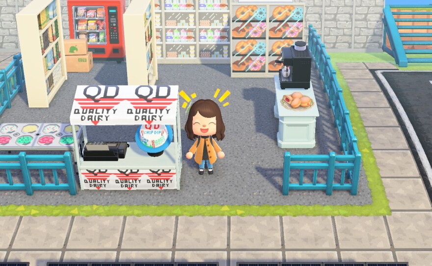 Sophia Saliby's Animal Crossing character does a laughing reaction in front of an area made to look like a Quality Dairy Store. There is a register with QD Chip Dip and Quality Dairy logos, ice cream and shelves of donuts and other snacks.