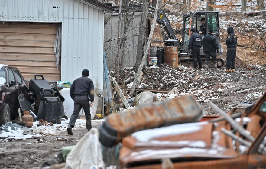 State Police troopers observe as an excavator digs on a property in Noxen. 