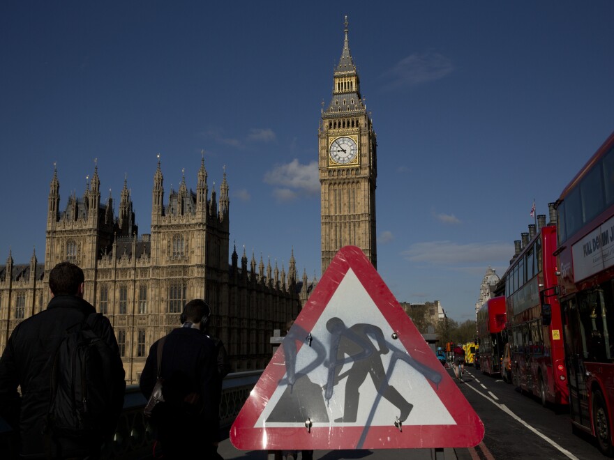 Big Ben resides in the Elizabeth Tower of the Houses of Parliament, seen in the distance behind a construction sign on Westminster Bridge.