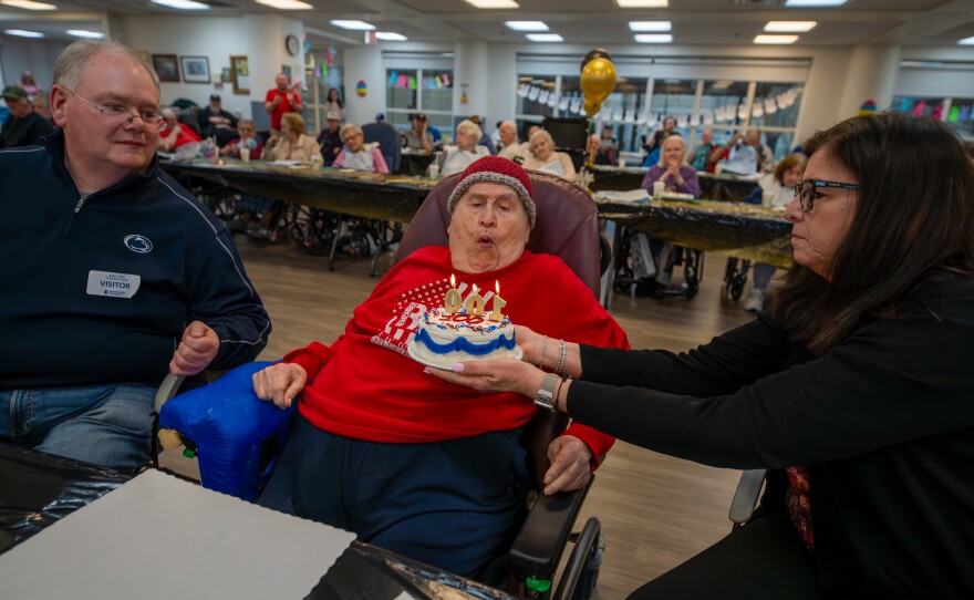 James "Sudsy" Fiume blows out candles while celebrating his 100th birthday.