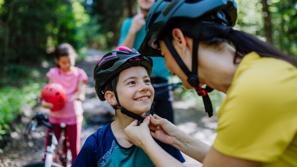 A young family with little children preapring for bike ride, standing with bicycles in nature.