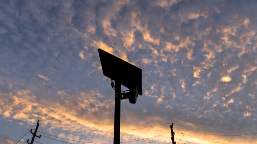 looking up at a ALPR with dramatic orange streak and other orange sports in the dusk sky