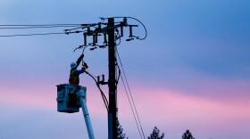 A Pacific Gas & Electric employee repairs a power line in fire-ravaged Paradise in 2018.