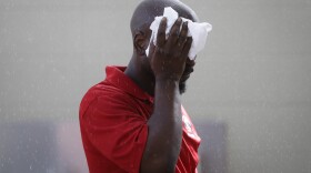An employee wipes his head under a misting station at Great American Ball Park in 2015.
