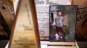 A photo of Isaac Berger with his cat, Frownie, is propped up in his bedroom near his college diploma and a state math competition trophy. A mathematical formula found by police on his computer seemed to calculate how many pills Isaac could take each day without dying.