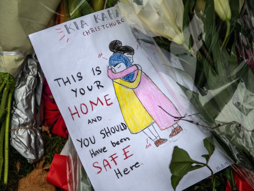 A message is left among flowers and tributes by the wall of the Botanic Gardens in Christchurch, New Zealand.