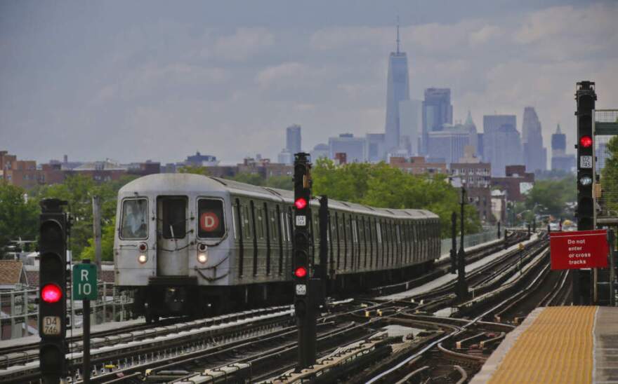 A subway approaches an above ground station in the Brooklyn borough of New York with the New York City skyline in the background. (Bebeto Matthews/AP)