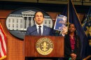 Louisville Mayor Craig Greenberg holding up a printed copy of his proposed plan to implement the consent decree reforms without the federal government.