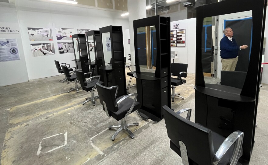 Five barber/salon stations are set out in the future space of Miss Julie's School of Beauty, a cosmetology school for survivors of or people at risk of human trafficking. Renderings tacked on the wall show how the space might look. Ken Greene, director of commercial development for Sibley Square, is reflected in the mirror of the station in the foreground.