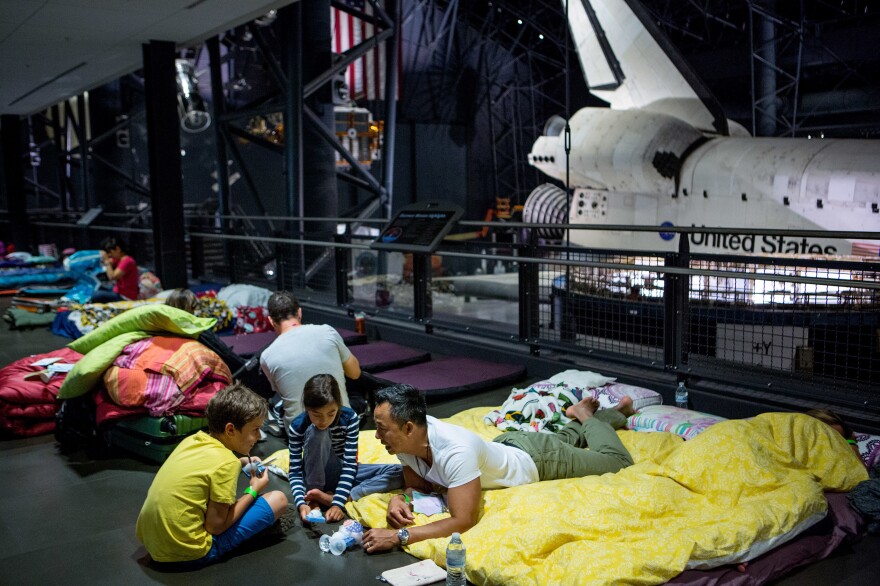 Soraya Okely (center), her dad, Cadeyrn (right), and friend Eli Shroads, 9, examine their handmade satellites before bed.