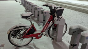 A snow covered Red Bike sits alone in a docking station along Mehring Way, in the predawn hours of January 19, 2024.
