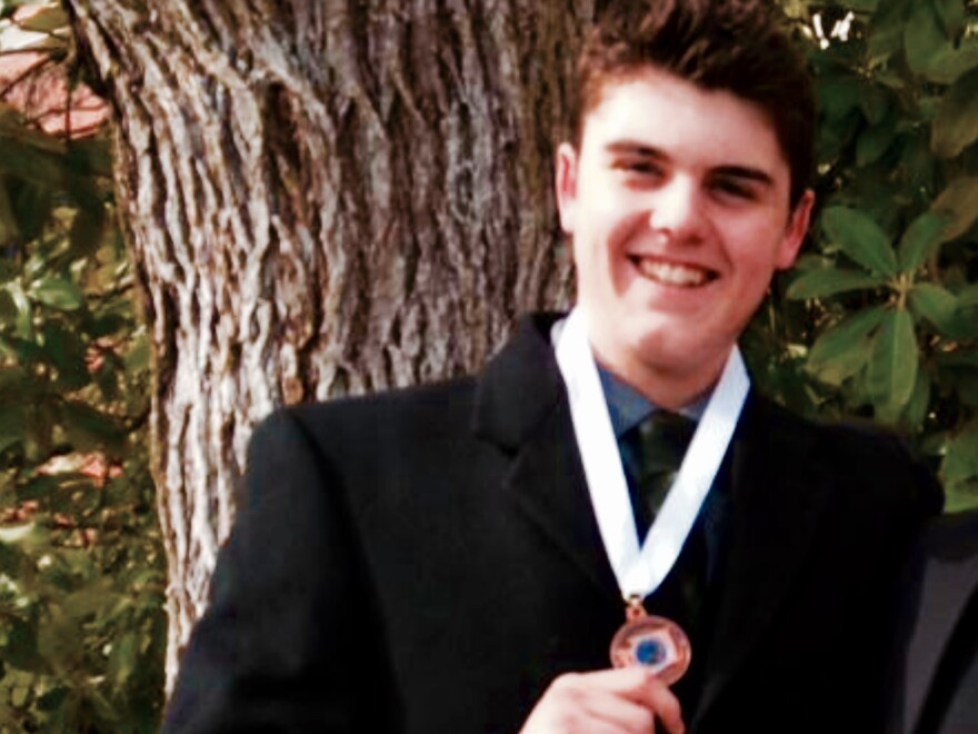 Calvin Clark in his senior year of high school, holding up a medal for the state debate championship.