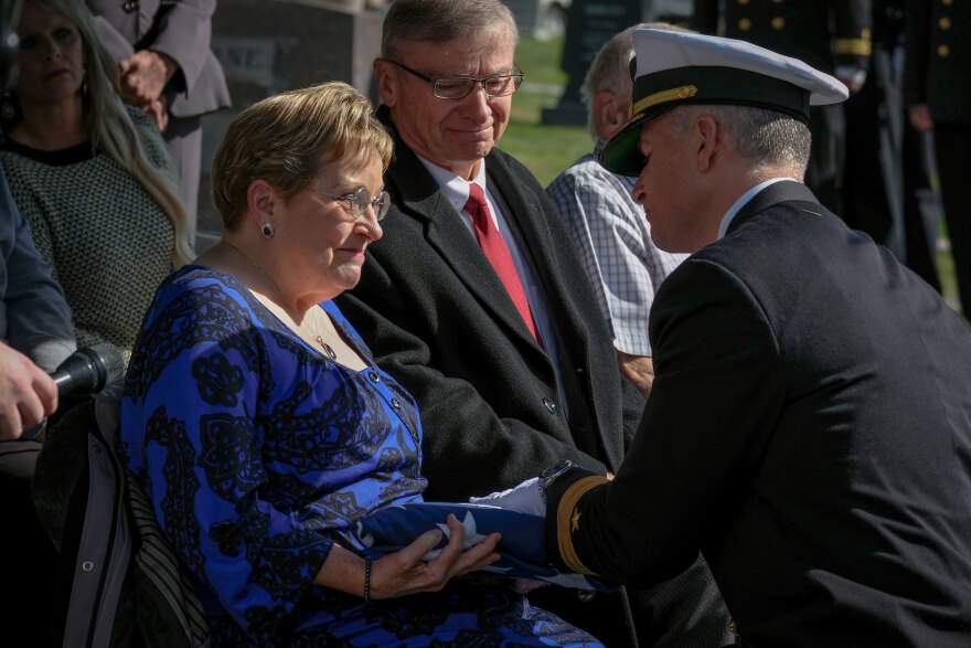 Terri Trick receives a folded American flag at the funeral of her uncle, naval aviator Howard Allen Holding, Oct. 17, 2025. Holding was shot down over the South Pacific Ocean during WWII, and his remains were not identified until June 10, 2025.