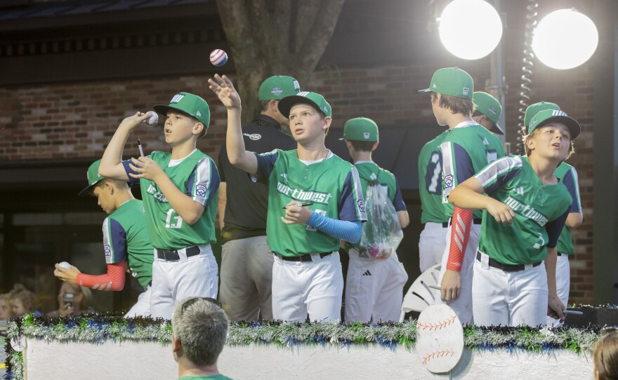 Players from the Northwest region team throw autographed balls back to the crowd during the Little League World Series parade.