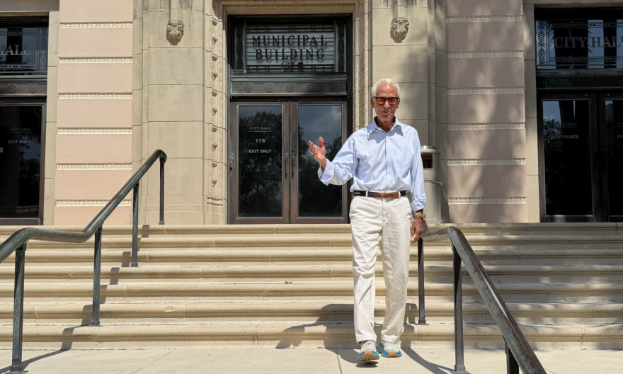 Old man with grey hair walks down city hall steps 