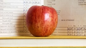 Stack of books and apple with a vintage report card