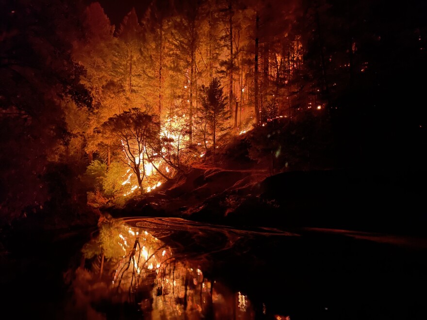 The Caldor fire light up the forest at night.