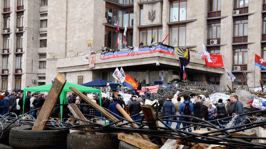 Pro-Russian protesters surround a barricade made by used tires and barbed wire Friday in Donetsk, Ukraine. Pro-Russian protesters took control of the government building and have held it since Sunday.