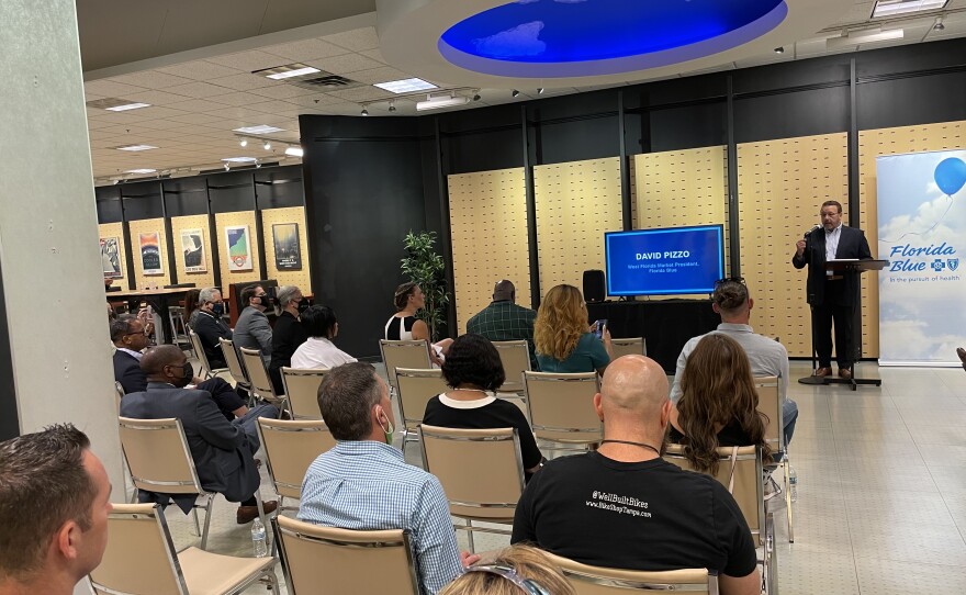 A group of people sit in chairs facing a screen and presentation.