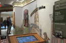 A painted wall says, "Citizen station," with panels about the three branches of government. In the foreground is an interactive display and corded telephone.