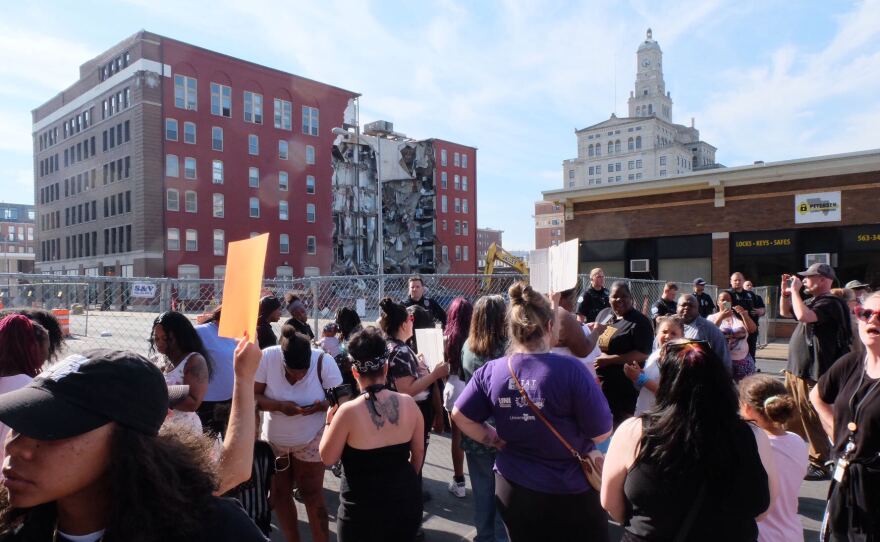 Protesters stand outside the collapse site of an apartment building in Davenport.