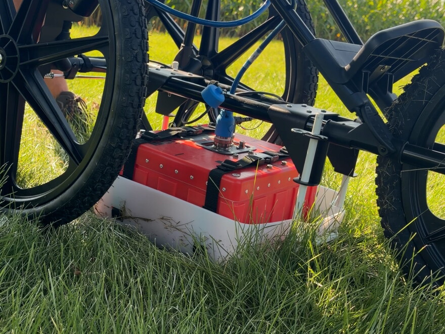 an orange box sits on the ground below a tricycle