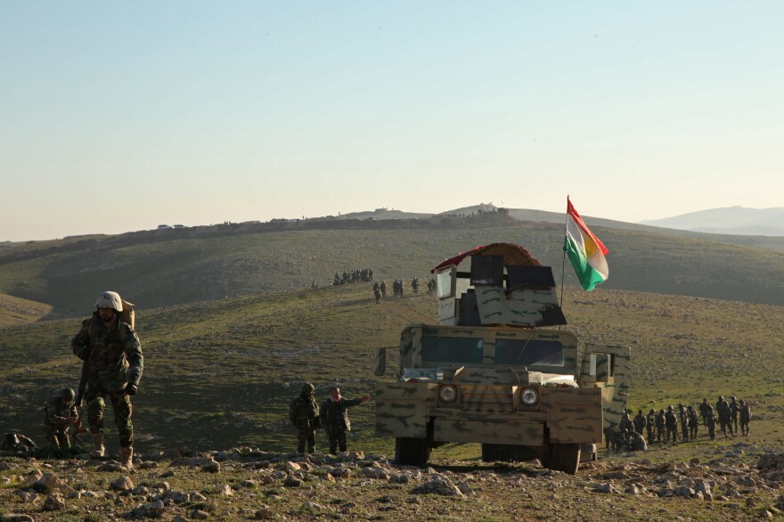 Kurdish peshmerga fighters walk with their weapons as they take control of the area, on the outskirts of Mosul on Feb. 6.