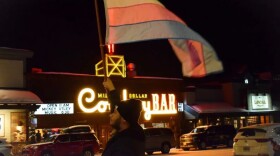 Jackson resident Mars William Silva waves a pink and blue flag — the transgender colors — in front of the Cowboy Bar near town square on Feb. 27, during a vigil for Nex Benedict, a nonbinary teenager who recently died in Oklahoma.