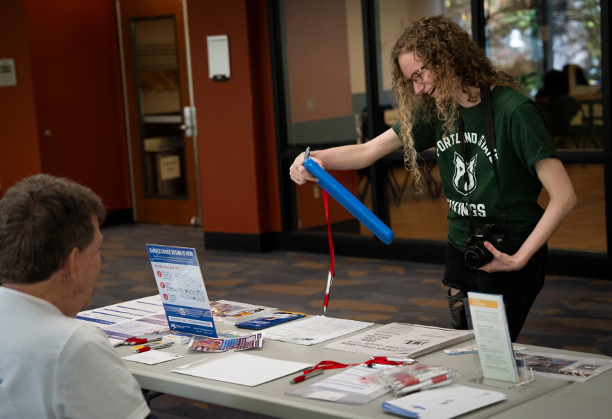 PSU student Maddy Mills checks out the voter registration tables at Portland State University on Oct. 6, 2026. The Puppies at the Polls event was hosted by the university in a bid to incentivise students to check out the nearby voter registration tables ahead of the election.