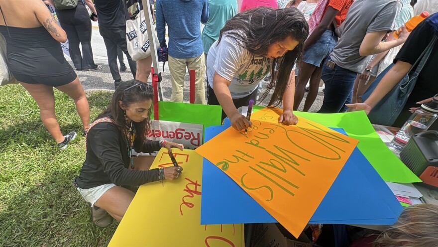 Jennifer Namath (left) helps make signs for protesters Sunday at the site of a proposed immigration detention center in the Big Cypress National Preserve.