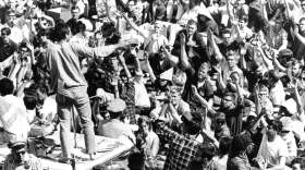 Standing atop the crushed roof of a campus police car, a University of California student asks Cal students to identify themselves during third day of Free Speech Movement demonstrations at Berkeley. Rita Lavelle protested against the protesters at Berkeley. (AP Photo)