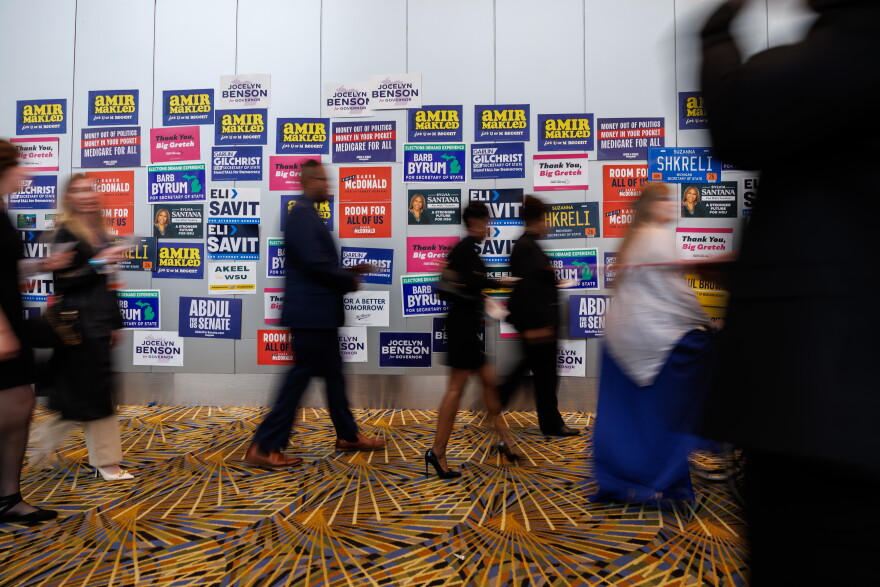 People walk by a wall that is plastered with campaign signs