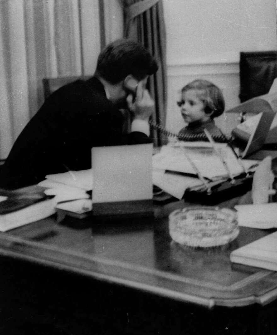 In this photo from March 1961, Kennedy talks on the phone with his wife, Jacqueline Kennedy, with their daughter, 3-year-old Caroline, at his side.