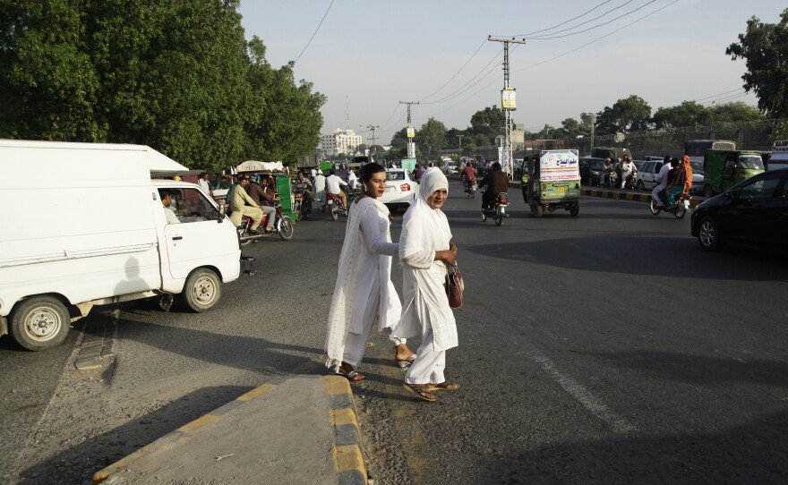 Transgender women walk toward traffic to beg motorists for cash in Lahore. Many believe transgender women have the power to bless and curse humans — a residual belief from when they were seen as sacred.