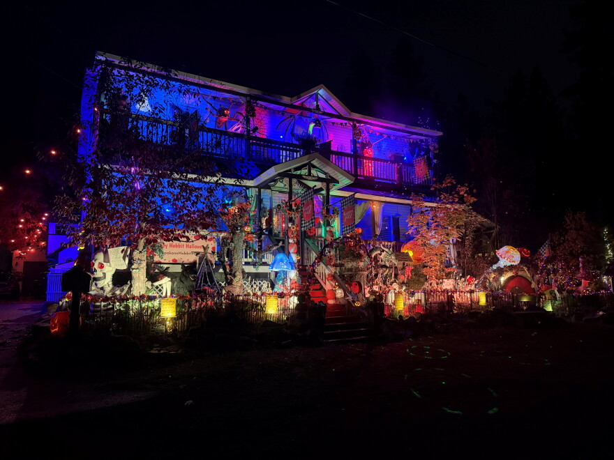 A large house at night is lit up with lights from Halloween decorations.