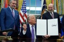 Flanked by Sen. Ted Cruz R-Texas, left, and Secretary of Commerce Howard Lutnick, President Donald Trump displays his signed AI initiative in the Oval Office of the White House, Thursday, Dec. 11, 2025, in Washington.