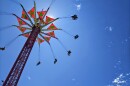 A photo looking up toward a carnival ride which features swings suspended from a tower. 