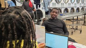Brendan Glover chats with Fabric Health worker Adrienne Jones inside a laundromat in Suitland, Maryland. Glover was uninsured at the time, and Jones said the company would help him find coverage.