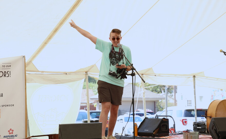William Clift speaks at the opening announcements of the 10th annual North Heights Porchfest on Oct. 10, 2026. He's standing on a flat bed trailer that's been made into a stage, speaking into a microphone.