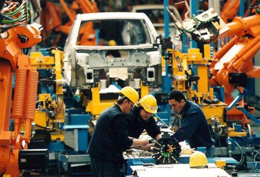 Two auto workers on an assembly line