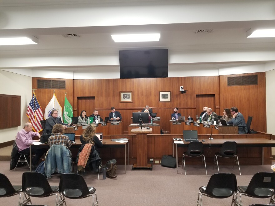 Councilors sit in behind the city hall rostrum