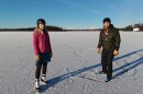 Two people skate on a snowy lake. 